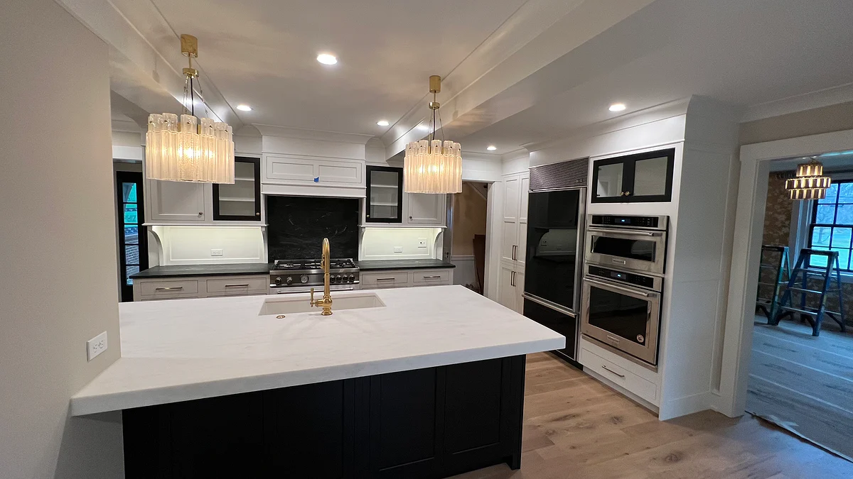 Custom white kitchen with a black island and integrated appliance wall