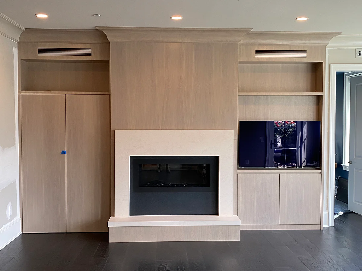 Custom pale wood media wall with shelving and an integrated fireplace