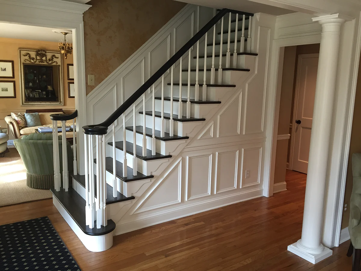 Detailed staircase with paneled millwork, turned balusters, and dark handrail