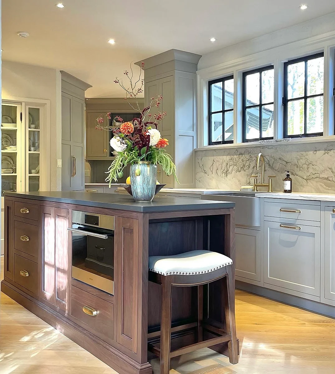 Warm wood furniture-style kitchen island surrounded by custom gray cabinetry